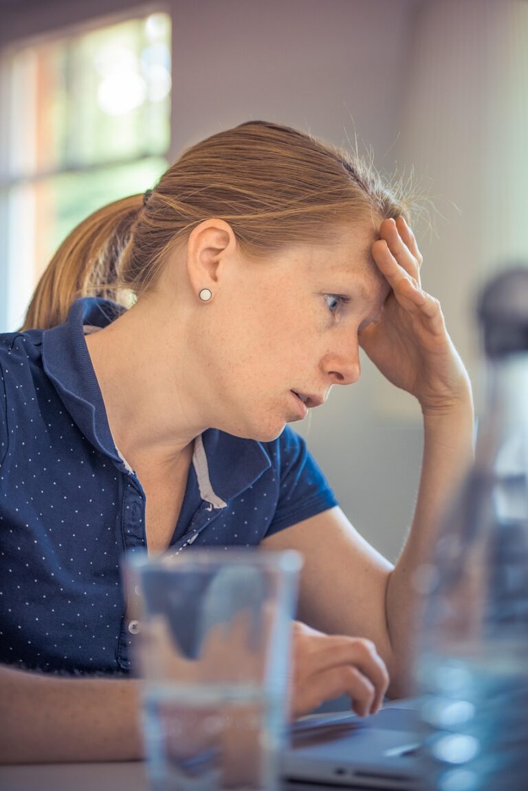 Donna stanca con la testa tra le mani, segno di stress e burnout del caregiver.