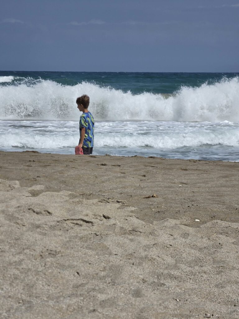 Bambino sulla riva osserva il mare mosso e le onde